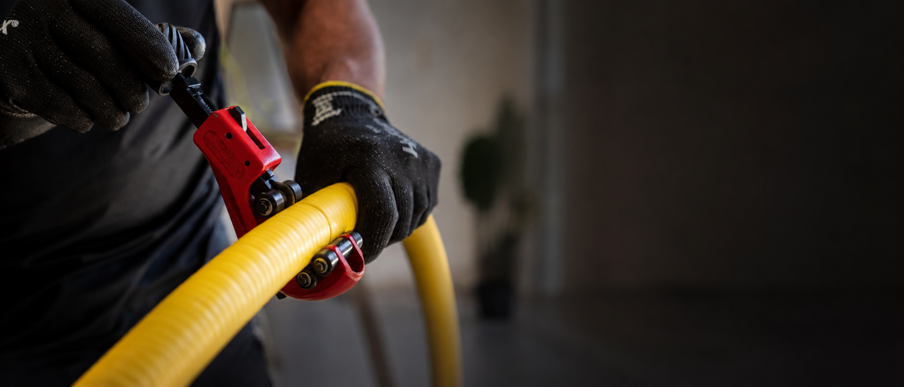 Gas installer cutting yellow Flexigas CSST pipe with a wheel cutter on site