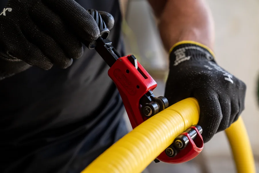 Installer cutting Flexigas pipe with a wheel cutter, no hot works