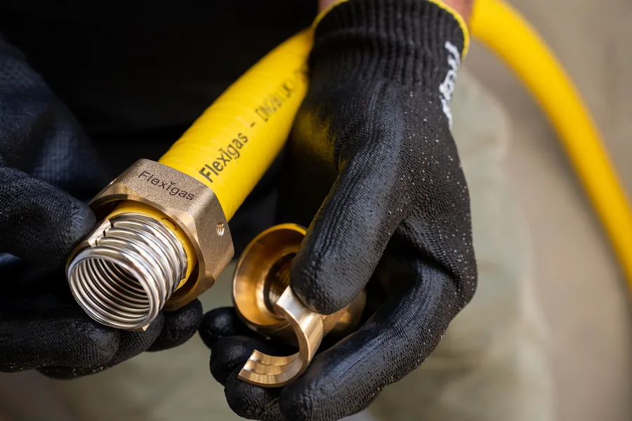 Hands tightening a Flexigas brass fitting with spanners