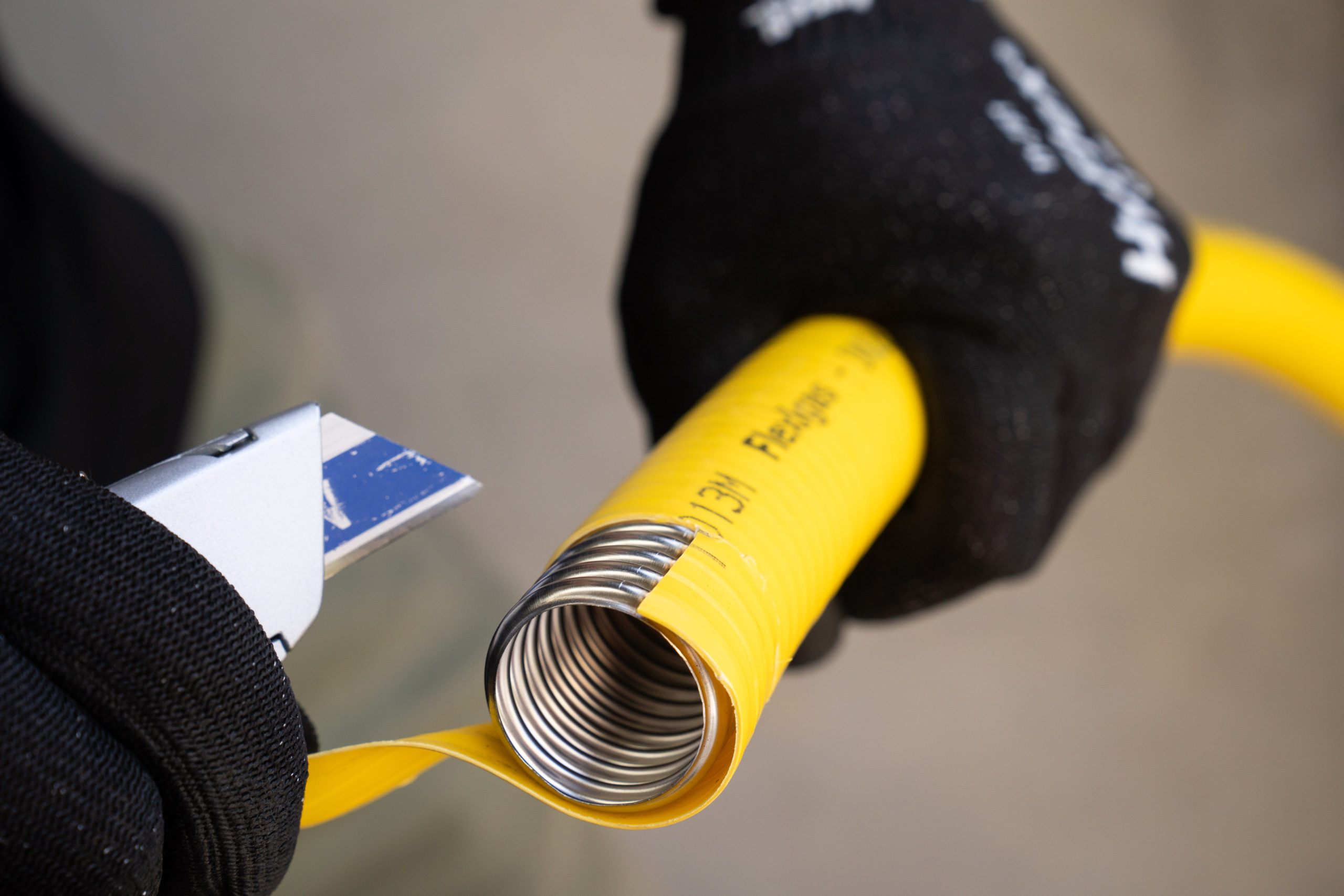 Removing the yellow cover with a utility knife to expose the stainless steel corrugations